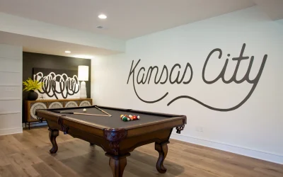 Kansas City-themed basement game area featuring a billiards table, stylish decor, and a prominent wall design that showcases "Kansas City" in a modern script.