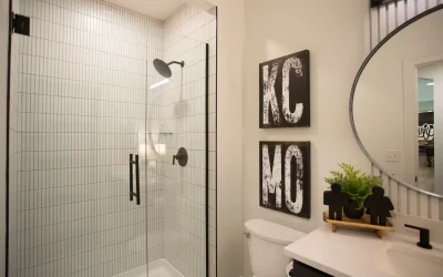 Modern bathroom featuring a glass-enclosed shower, high-contrast tile design, and decorative KC and MO wall art, reflecting a stylish and functional space in a Kansas City basement renovation.