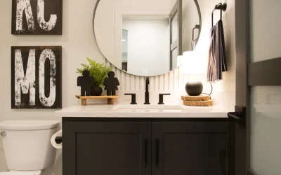 Modern bathroom sink area with matte black cabinetry, round mirror, decorative signage, and stylish accessories, showcasing a blend of functionality and aesthetic appeal in a remodeled Kansas City basement.